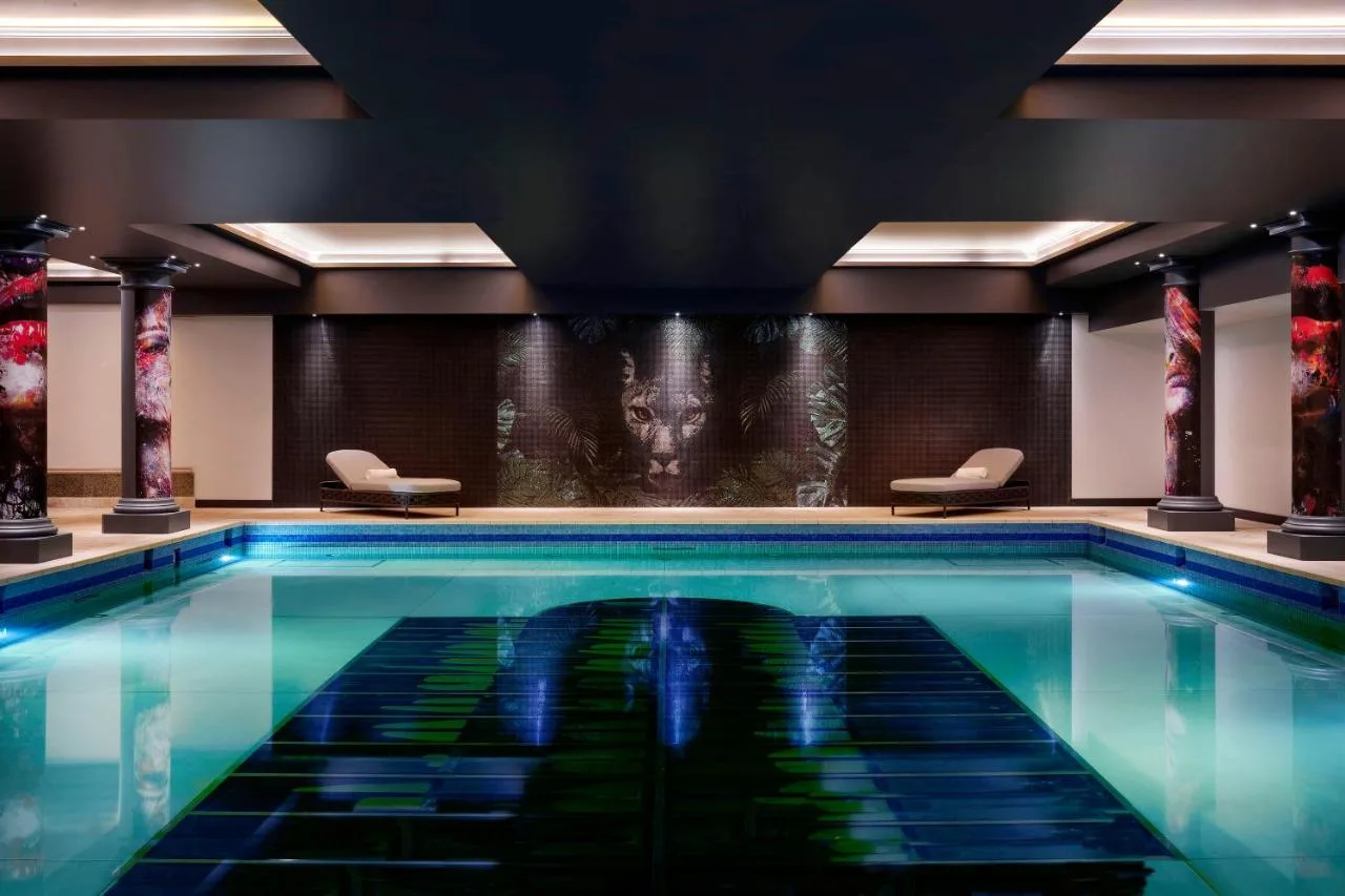 a swimming pool in a hotel with a painting on the wall at NYX Hotel London Holborn by Leonardo Hotels in London