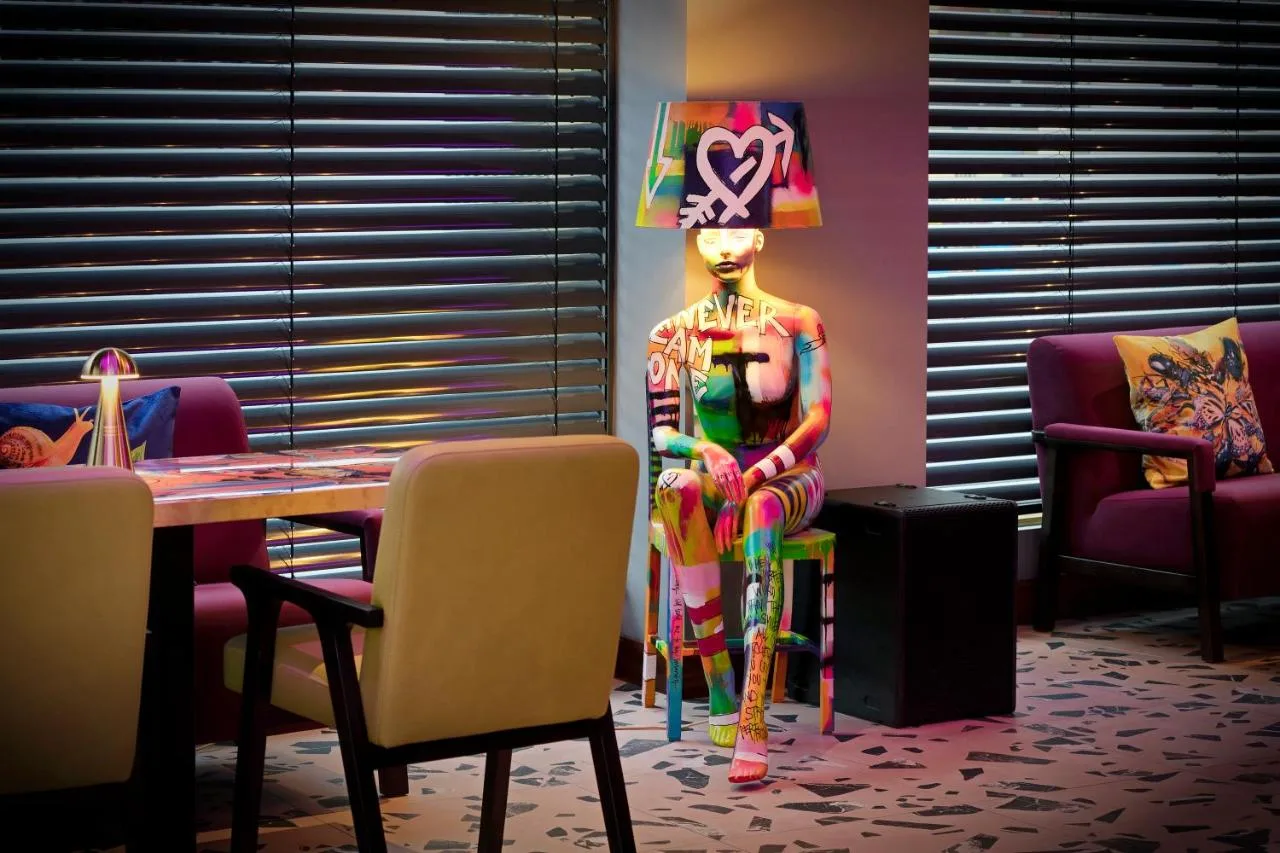 a statue of a man sitting on a chair next to a table at NYX Hotel London Holborn by Leonardo Hotels in London