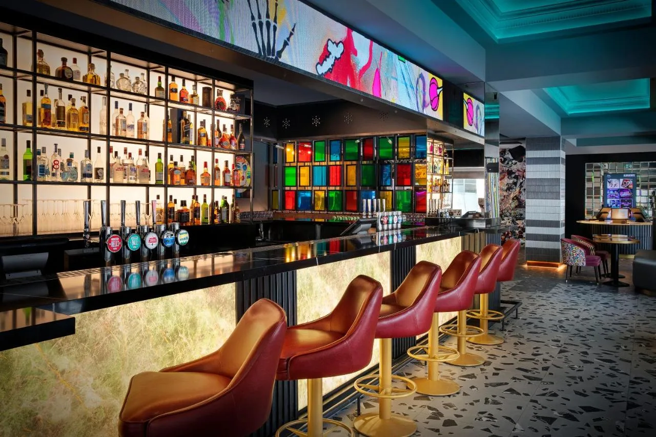 a bar with leather chairs and bottles of alcohol at NYX Hotel London Holborn by Leonardo Hotels in London